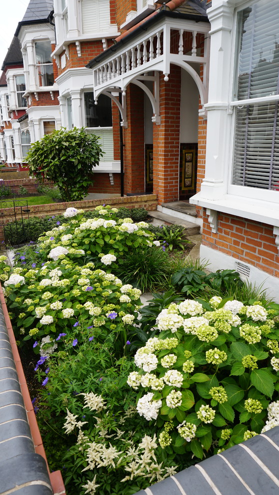 Immagine di un piccolo giardino formale classico in ombra davanti casa in estate con un ingresso o sentiero e pavimentazioni in cemento