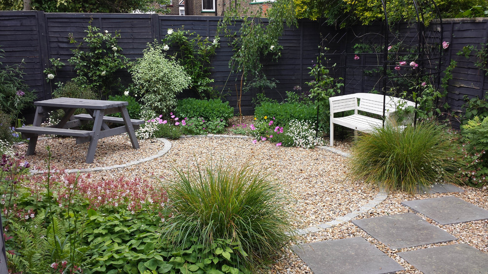 Small classic back formal fully shaded garden for spring in London with a garden path and natural stone paving.
