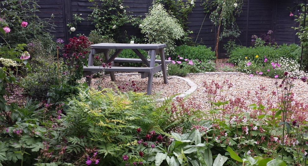 Cette image montre un petit jardin traditionnel au printemps avec une exposition ombragée et du gravier.