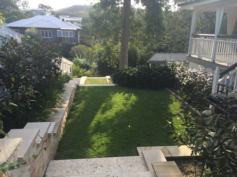 Inspiration för en mellanstor tropisk formell trädgård i delvis sol längs med huset, med naturstensplattor
