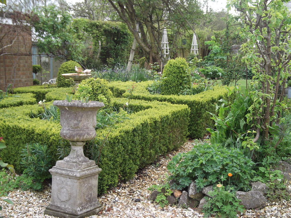 Ejemplo de jardín clásico pequeño con gravilla y jardín francés