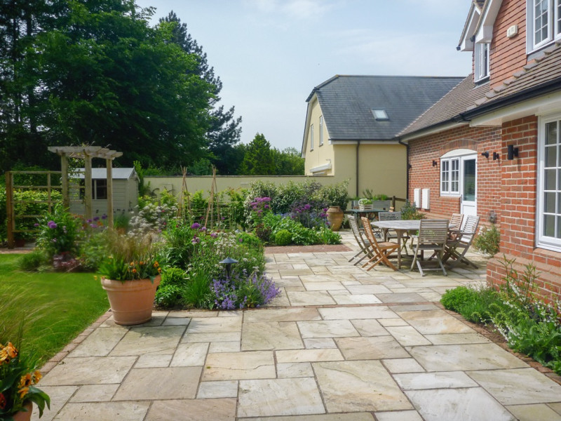 Medium sized traditional back garden for summer in Hampshire with natural stone paving.