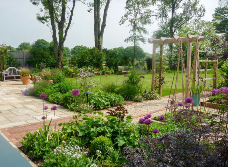 This is an example of a medium sized classic back garden for summer in Hampshire with gravel.