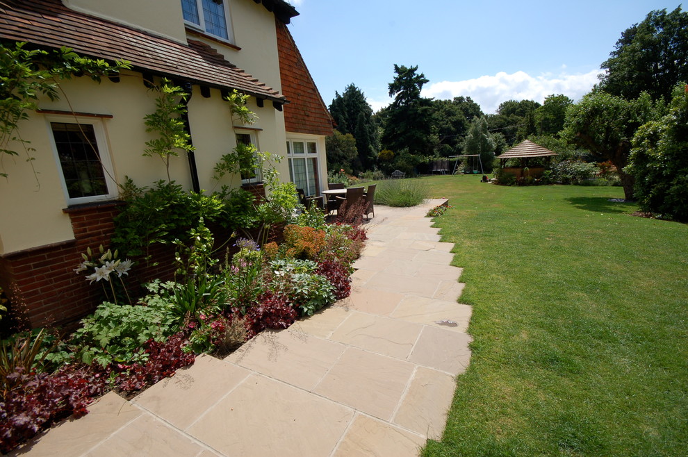Foto de jardín clásico grande en patio trasero con fuente y adoquines de piedra natural