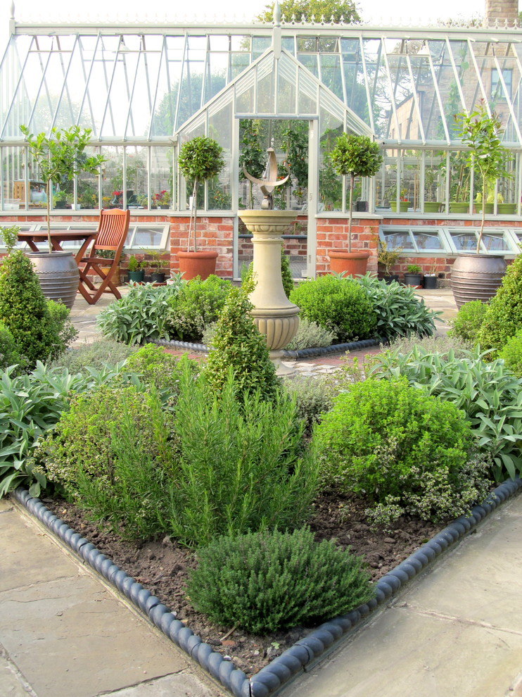 Aménagement d'un jardin potager arrière classique avec une exposition ensoleillée et des pavés en pierre naturelle.