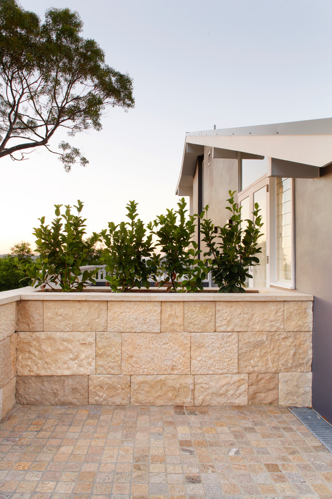 This is an example of a large traditional front driveway garden in Sydney with natural stone paving.