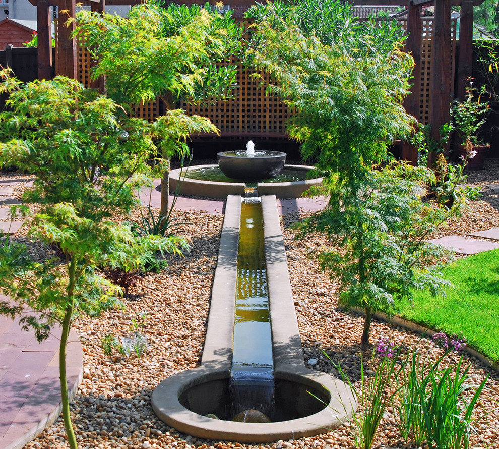 Imagen de jardín de estilo zen de tamaño medio en patio trasero con fuente y adoquines de piedra natural
