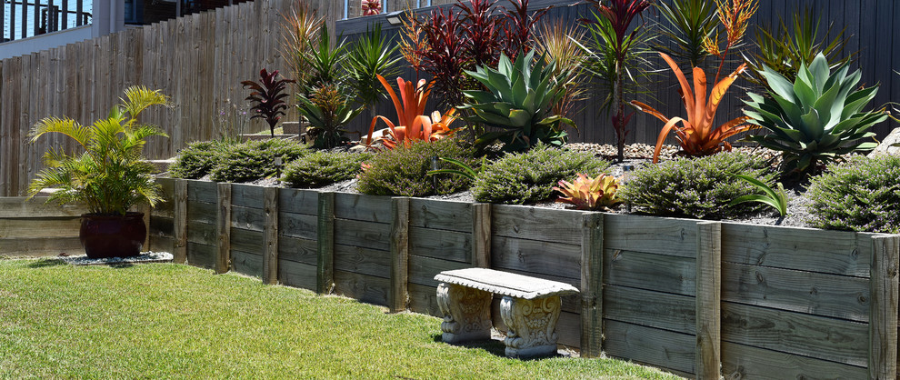 Inspiration for a medium sized world-inspired back full sun garden in Brisbane with a retaining wall and decking.