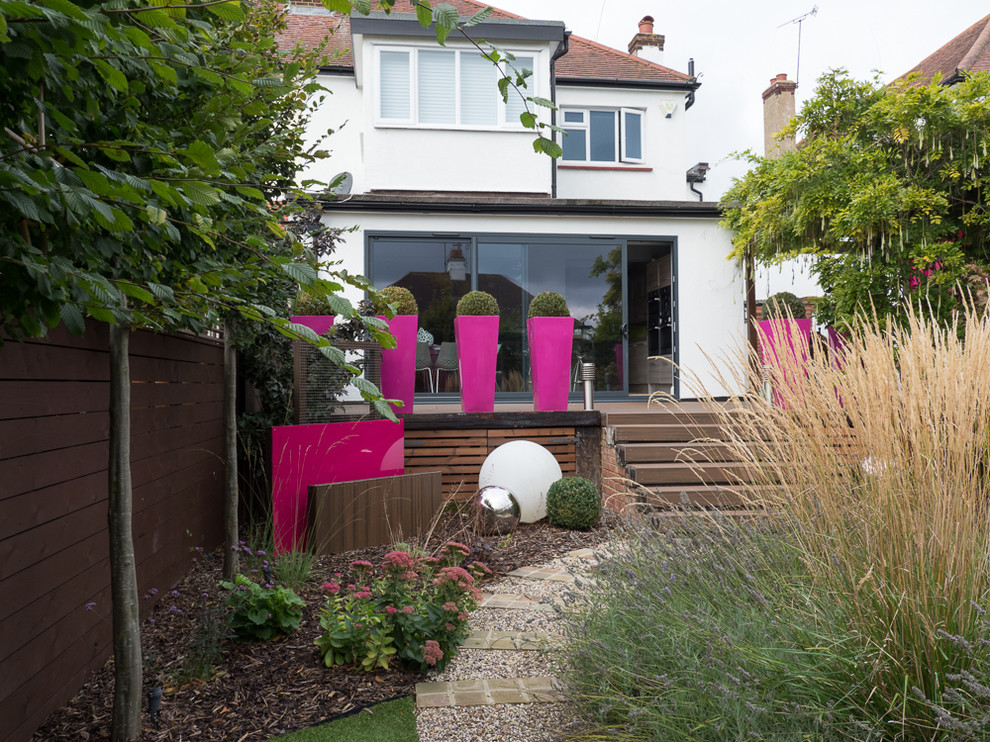 Cette image montre un jardin arrière minimaliste de taille moyenne avec une exposition ensoleillée et une terrasse en bois.