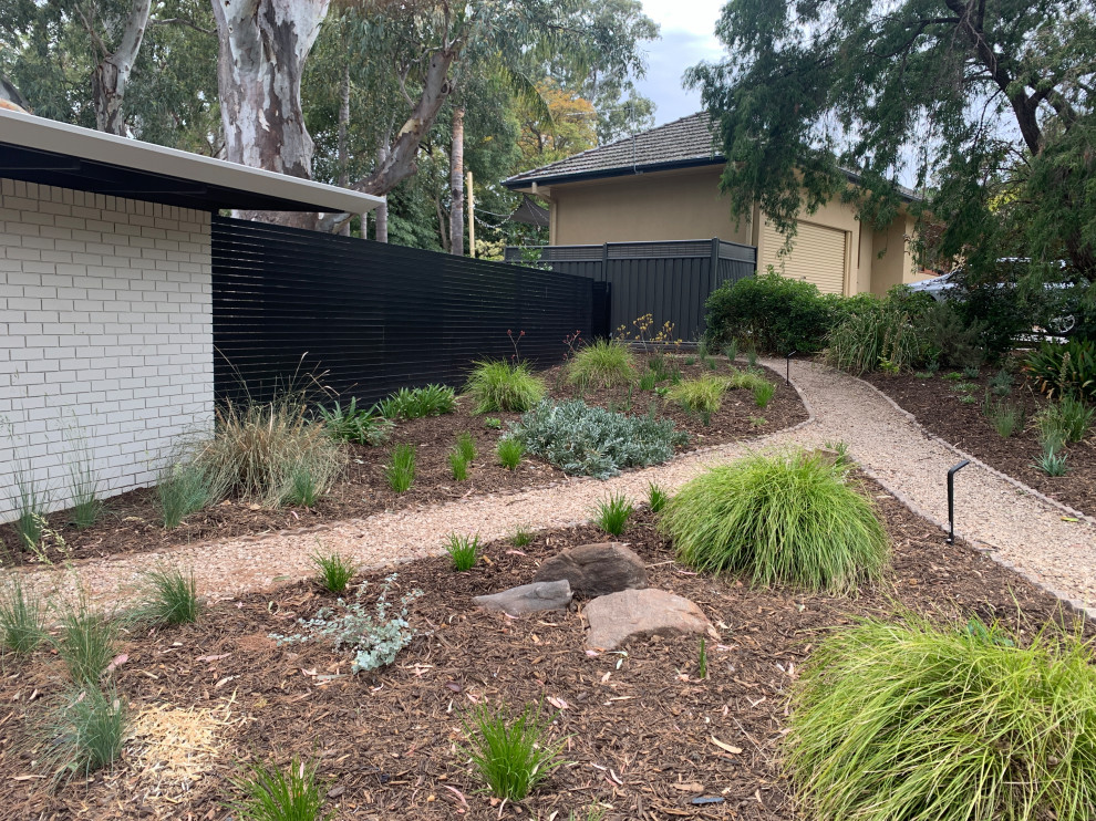 Medium sized retro courtyard xeriscape partial sun garden for spring in Adelaide with a garden path and natural stone paving.