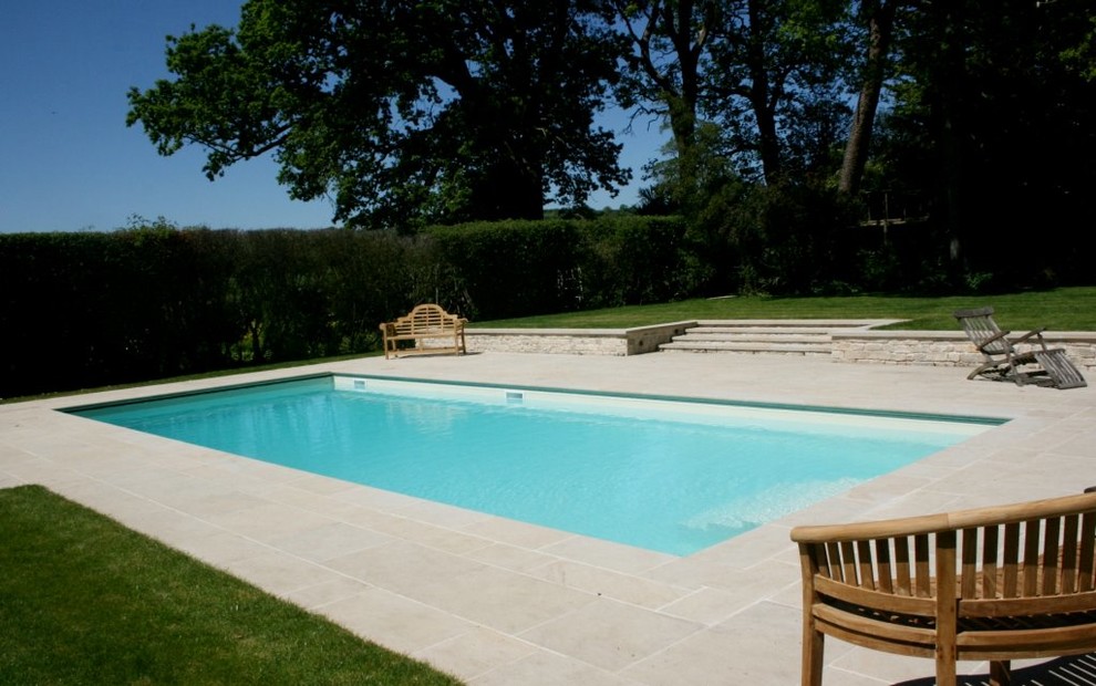 Modelo de piscina campestre de tamaño medio en patio trasero con adoquines de piedra natural
