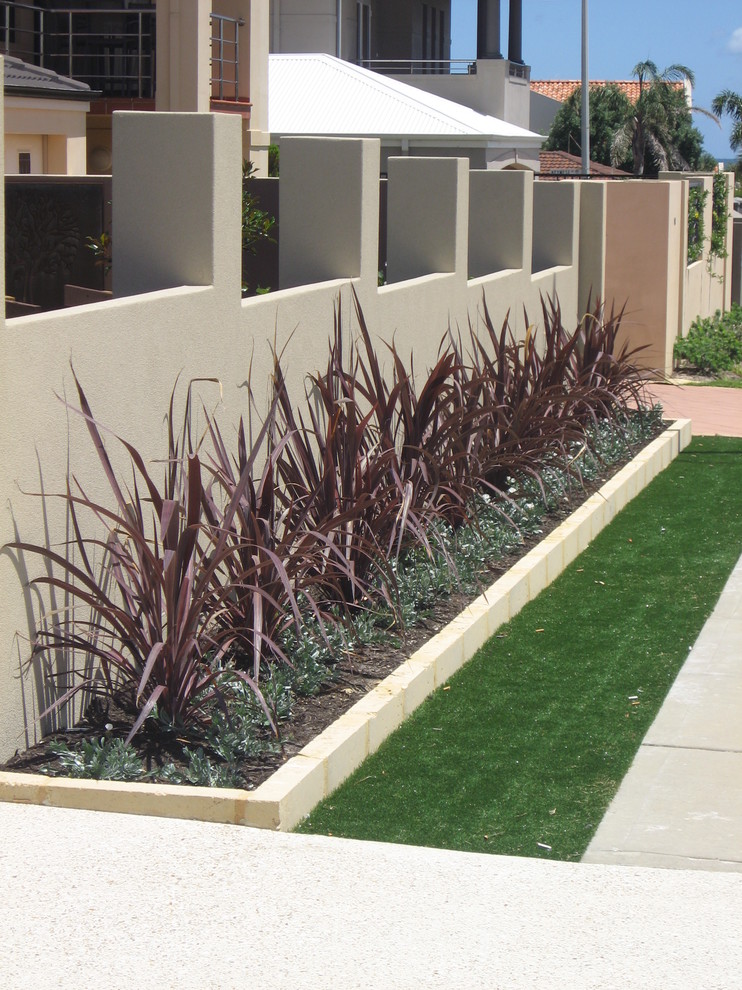 Photo of a medium sized contemporary front formal full sun garden for summer in Perth with a retaining wall and decking.