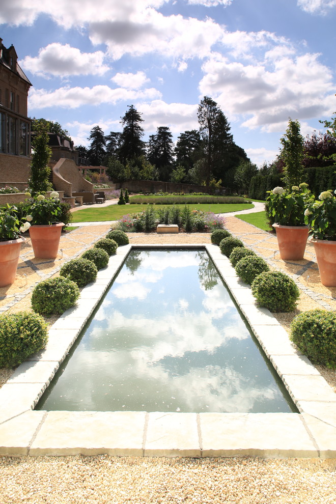 Cette image montre un jardin à la française méditerranéen l'été avec un bassin, une exposition ensoleillée et du gravier.