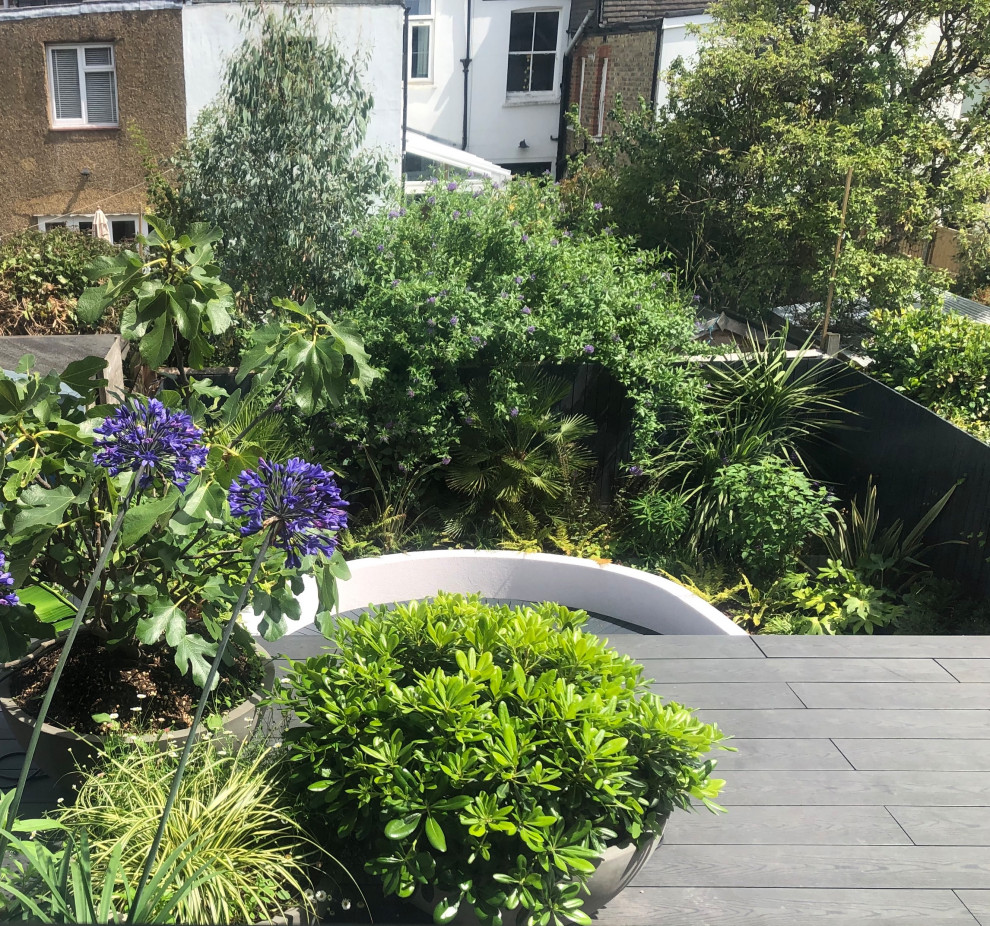 На фото: маленький солнечный, летний регулярный сад на заднем дворе в современном стиле с уличным камином, хорошей освещенностью и настилом для на участке и в саду с