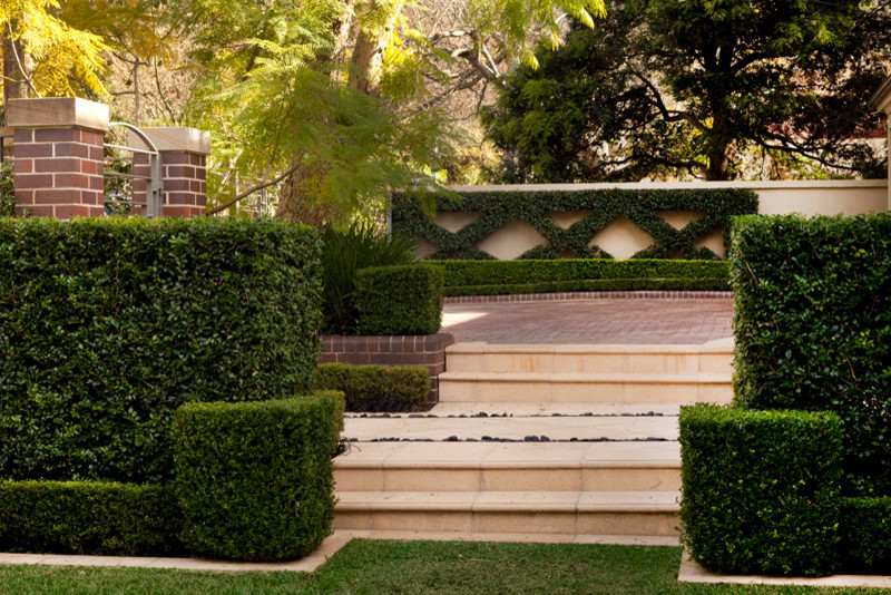 Bild på en stor funkis formell trädgård framför huset, med en trädgårdsgång och naturstensplattor
