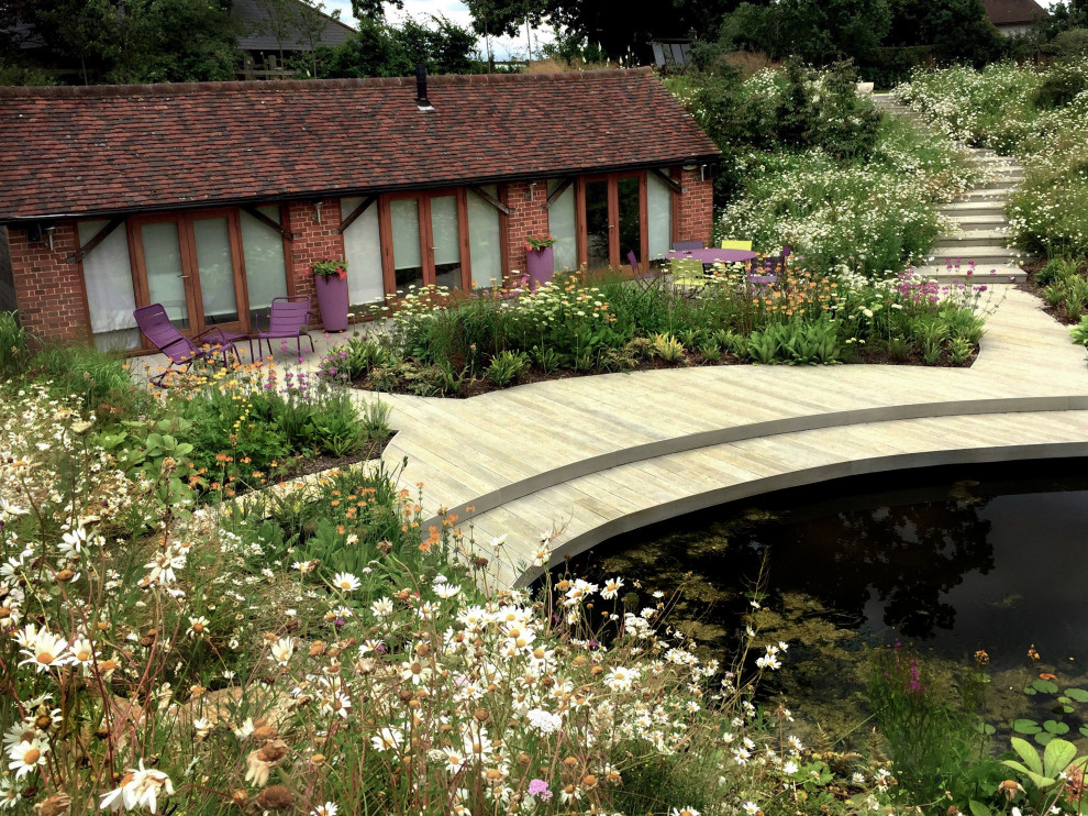 Idée de décoration pour un grand jardin latéral design l'été avec un massif de fleurs, une exposition ensoleillée et une terrasse en bois.