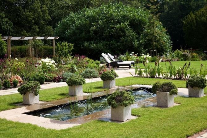 Inspiration for a large contemporary back full sun garden in London with a water feature and natural stone paving.