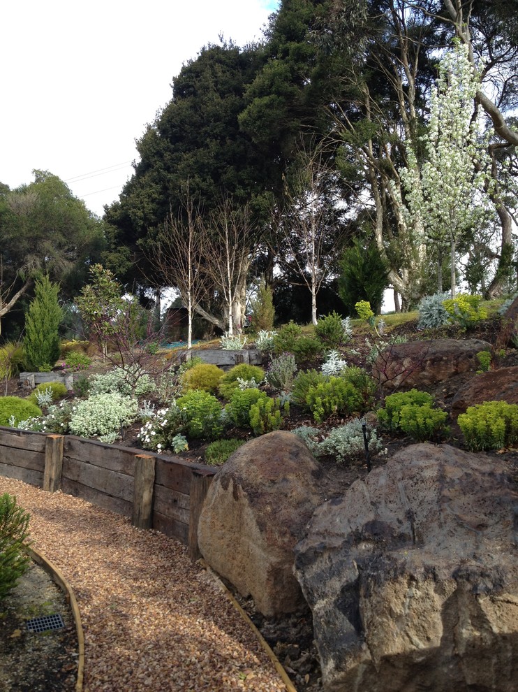 На фото: участок и сад на склоне в современном стиле с покрытием из гравия и камнем в ландшафтном дизайне