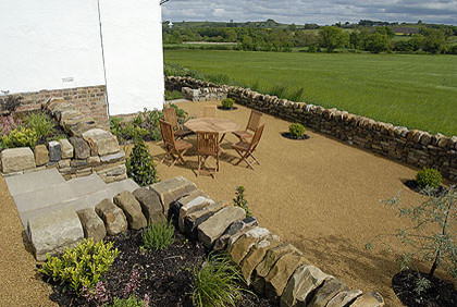 Cette photo montre un grand jardin arrière éclectique avec un mur de soutènement, une exposition ensoleillée et des pavés en pierre naturelle.