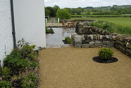 Cette image montre un grand jardin arrière bohème avec un mur de soutènement, une exposition ensoleillée et des pavés en pierre naturelle.