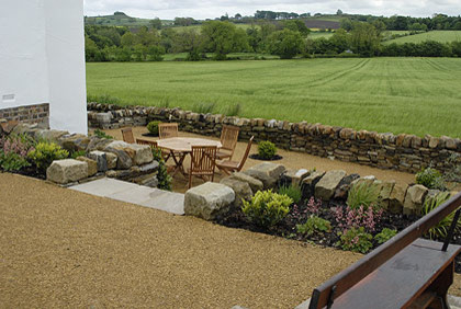 На фото: большой солнечный участок и сад на заднем дворе в стиле фьюжн с подпорной стенкой, хорошей освещенностью и покрытием из каменной брусчатки