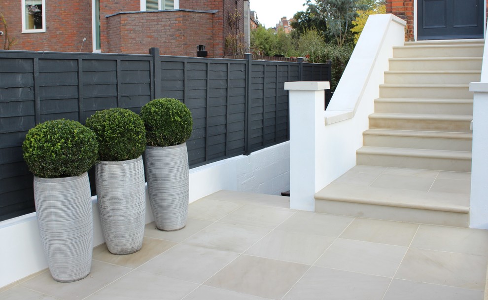 Photo of a medium sized contemporary front full sun garden fence in London with natural stone paving.