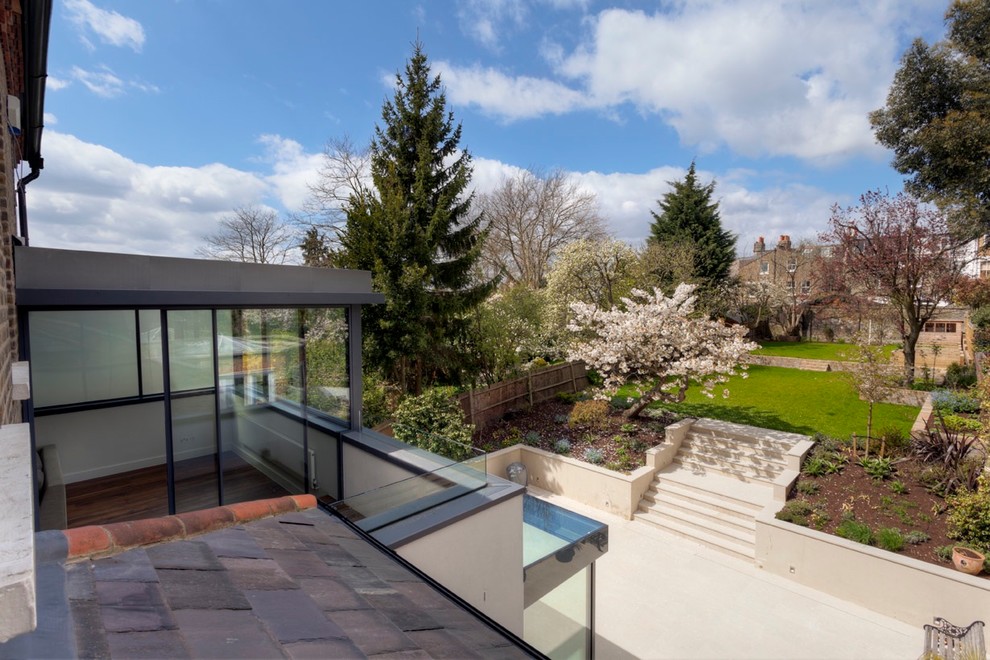 Geometrische, Große, Halbschattige Moderne Gartenmauer im Sommer, hinter dem Haus mit Natursteinplatten in London