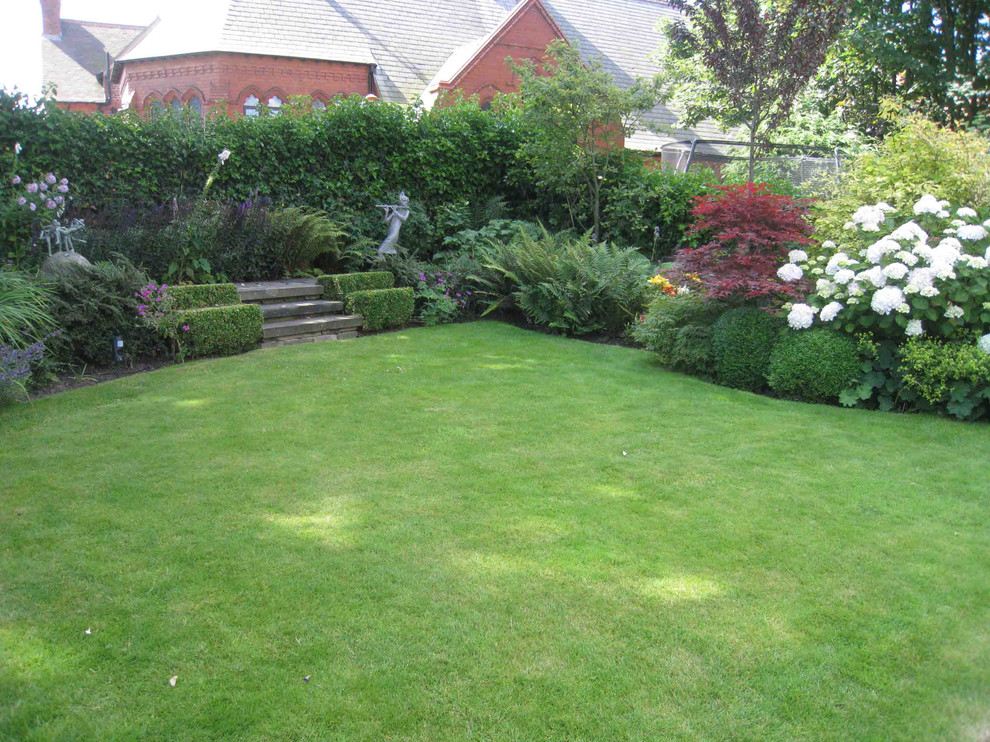 Photo of a medium sized contemporary back partial sun garden in Cheshire with natural stone paving.