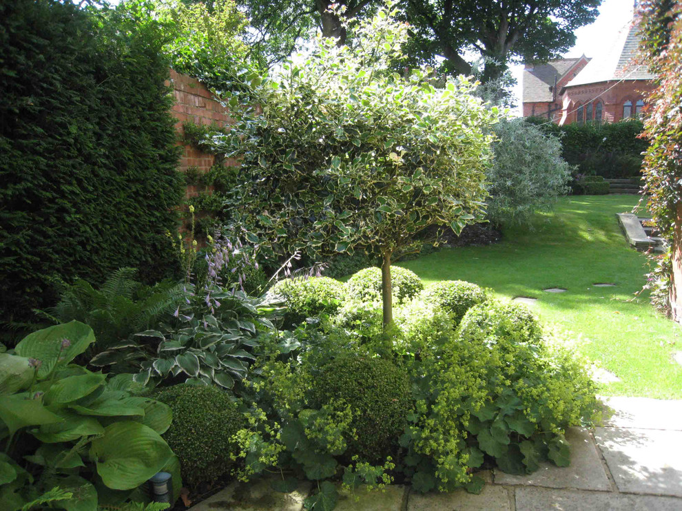 Inspiration pour un jardin arrière design de taille moyenne avec une exposition partiellement ombragée et des pavés en pierre naturelle.