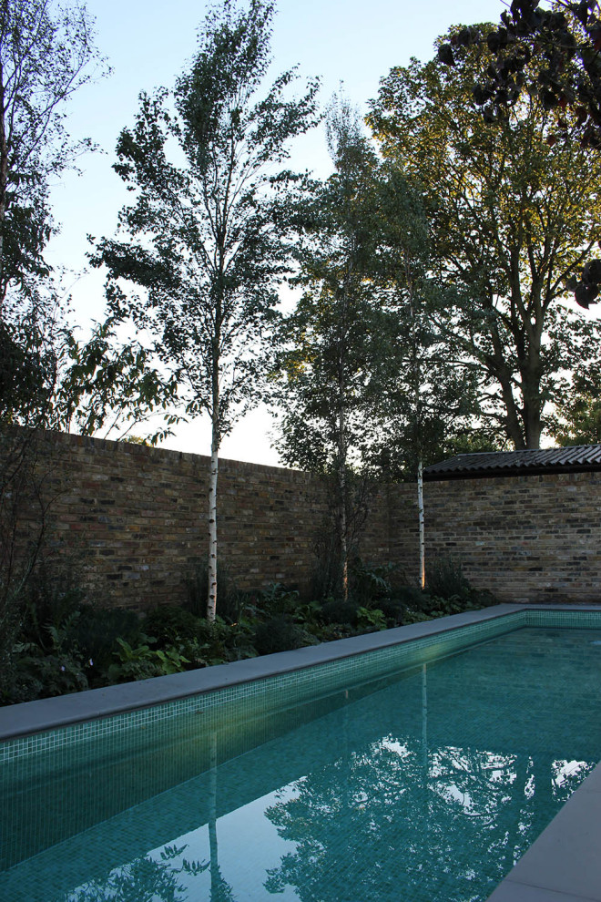 This is an example of a mid-sized contemporary full sun backyard brick landscaping in London for summer.