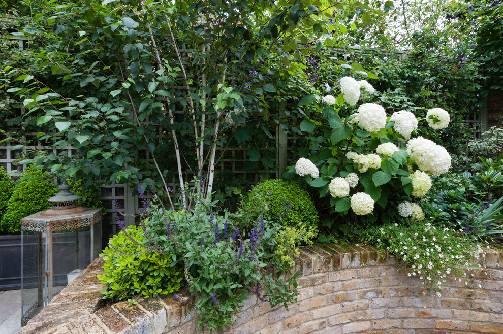 Kleiner, Halbschattiger Klassischer Garten im Innenhof im Frühling mit Sportplatz und Pflastersteinen in London