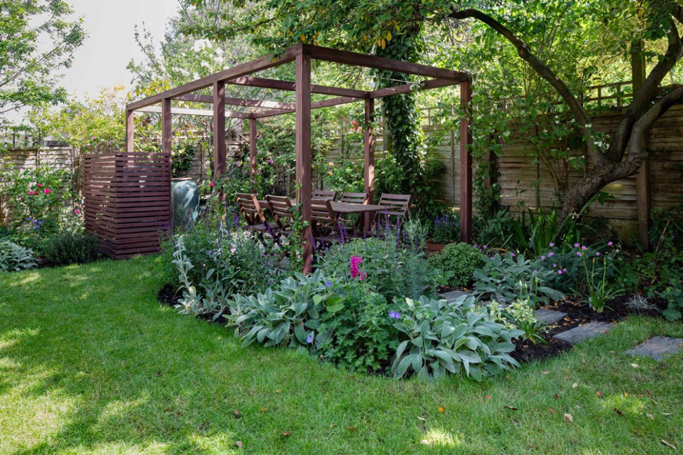 Cette image montre un jardin avec pergola arrière design de taille moyenne et l'été avec une exposition partiellement ombragée et une terrasse en bois.