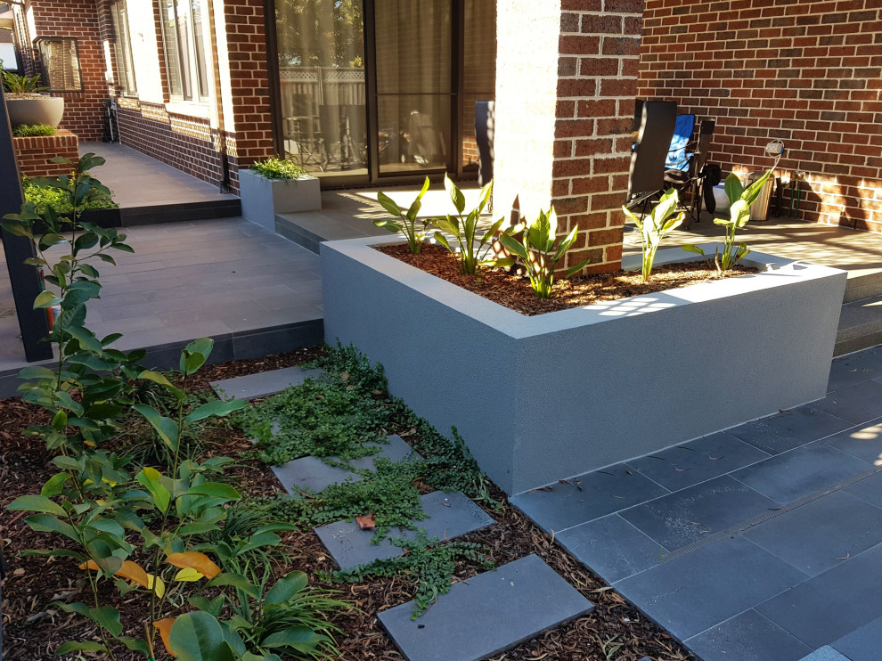 Inspiration for a medium sized modern back formal partial sun garden for summer in Melbourne with a flowerbed and natural stone paving.