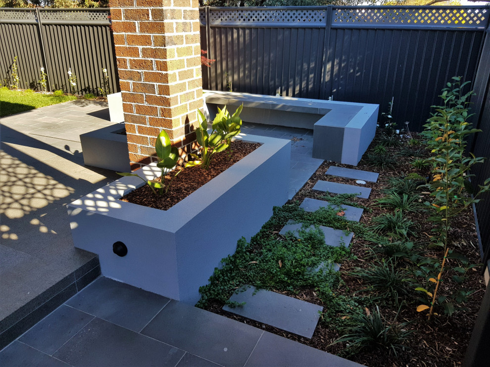 На фото: летний регулярный сад среднего размера на заднем дворе в стиле модернизм с клумбами, полуденной тенью и покрытием из каменной брусчатки