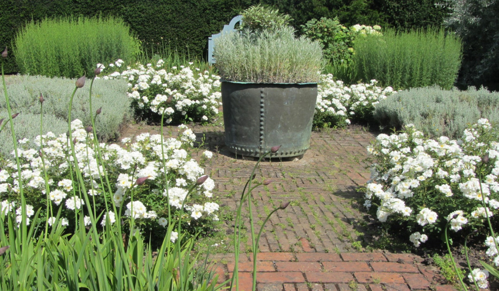 Imagen de jardín de estilo americano de tamaño medio en verano en patio con jardín francés, parterre de flores, exposición total al sol y adoquines de ladrillo