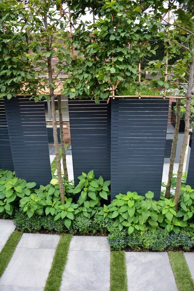 Réalisation d'un petit jardin sur cour design avec une exposition partiellement ombragée et des pavés en béton.