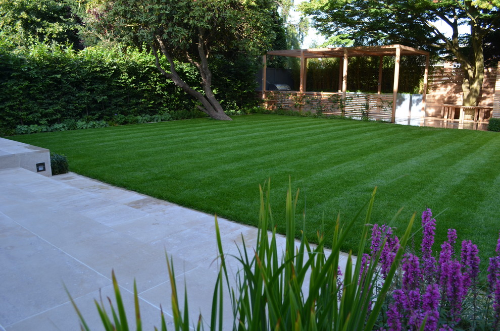 Contemporary back formal garden in London with natural stone paving.