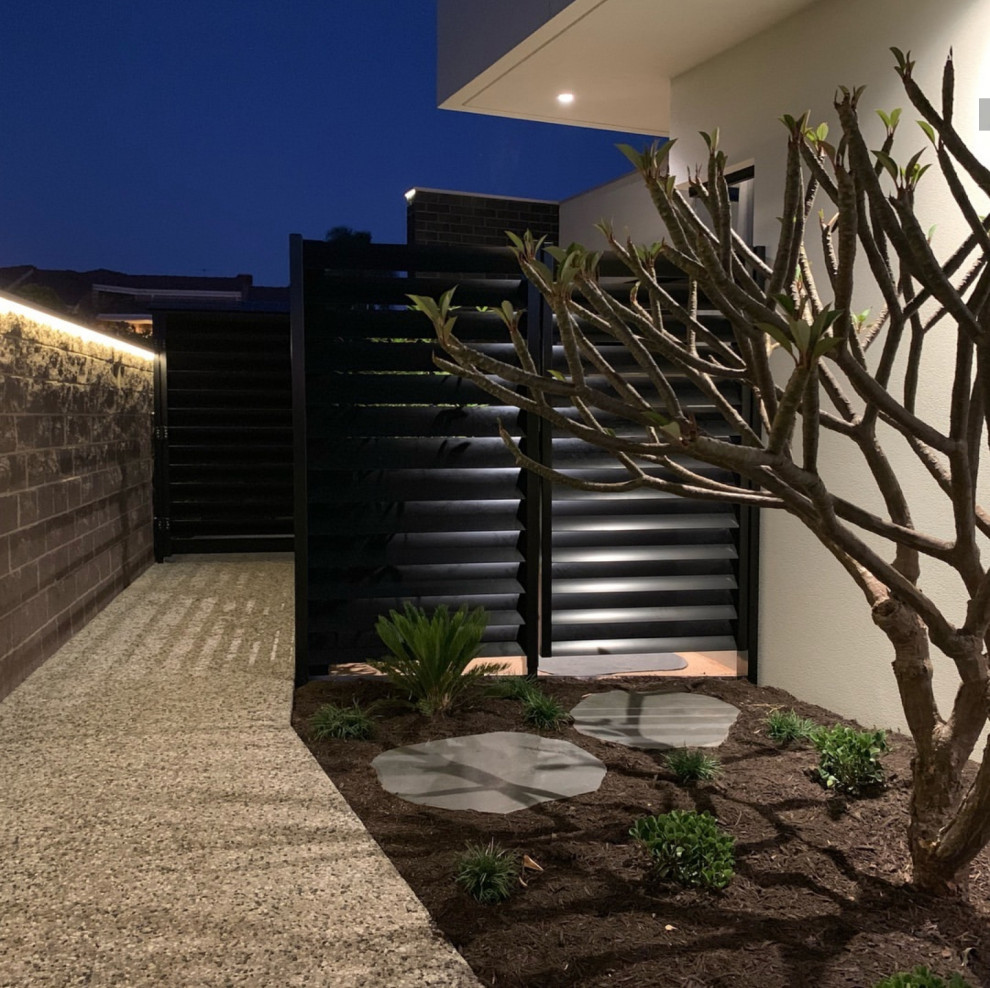 Idée de décoration pour un grand aménagement d'entrée ou allée de jardin latéral design au printemps avec une exposition partiellement ombragée, un gravier de granite et une clôture en pierre.