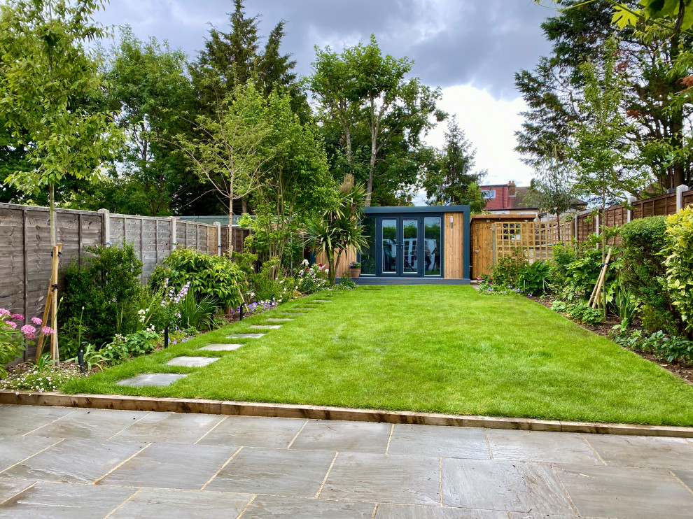 Mittelgroßer, Halbschattiger Moderner Garten im Sommer, hinter dem Haus mit Holzzaun in Surrey