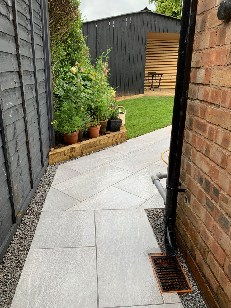 Medium sized industrial back formal full sun garden for summer in Buckinghamshire with a wood fence and natural stone paving.