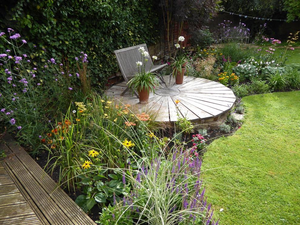 Réalisation d'un jardin arrière tradition avec une terrasse en bois.