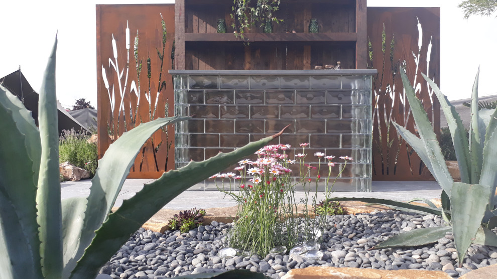 Diseño de jardín de secano mediterráneo pequeño en verano en patio trasero con paisajismo estilo desértico, exposición total al sol y adoquines de piedra natural