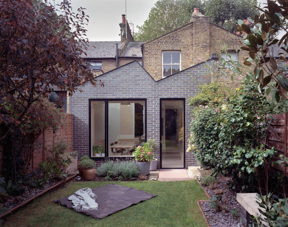 Kleiner, Halbschattiger Moderner Garten im Frühling, hinter dem Haus mit Rasenkanten, Natursteinplatten und Holzzaun in London