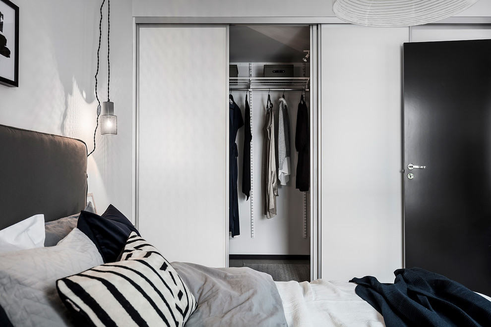 This is an example of a medium sized scandinavian gender neutral standard wardrobe in Gothenburg with flat-panel cabinets, white cabinets, light hardwood flooring and grey floors.