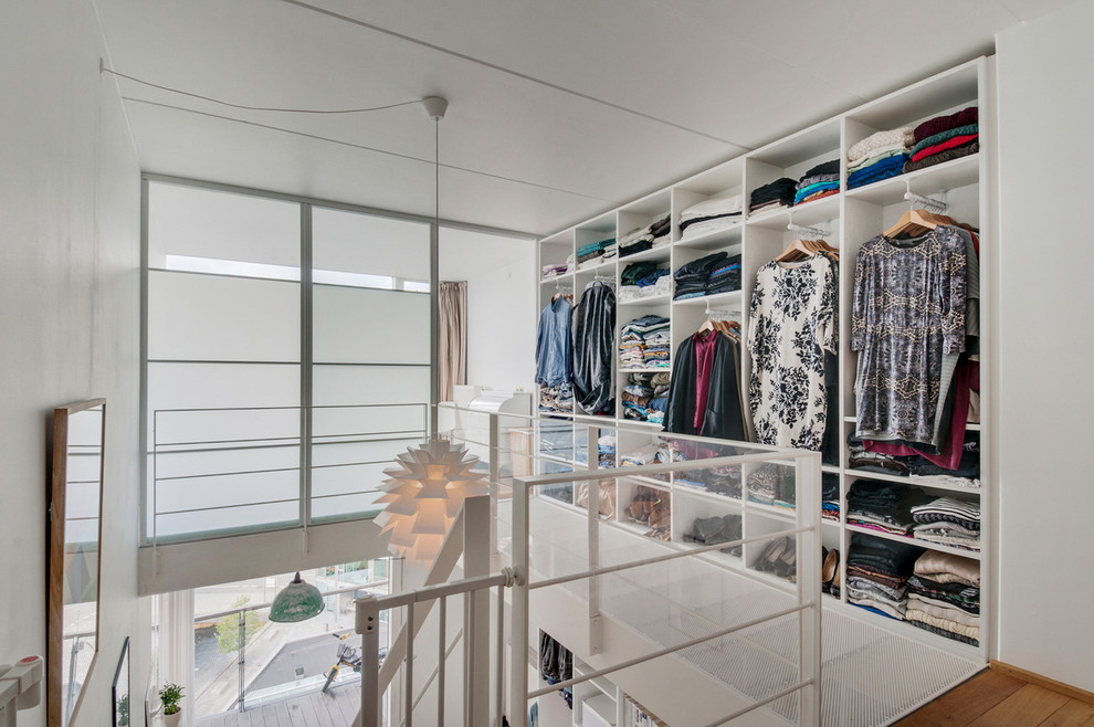 Foto de vestidor unisex nórdico de tamaño medio con armarios abiertos, puertas de armario blancas y suelo de madera clara
