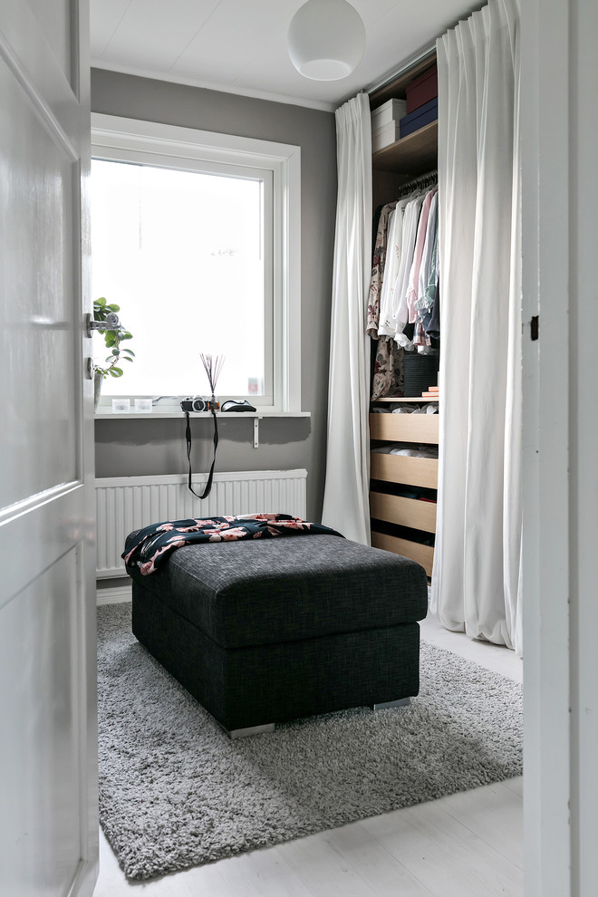 Ejemplo de armario vestidor de mujer nórdico de tamaño medio con suelo de madera clara y suelo gris
