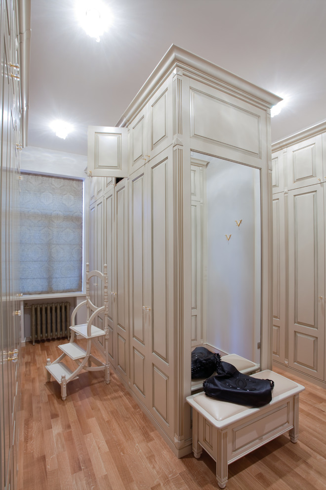 Neutrales, Großes Klassisches Ankleidezimmer mit Ankleidebereich, profilierten Schrankfronten, weißen Schränken und braunem Holzboden in Moskau