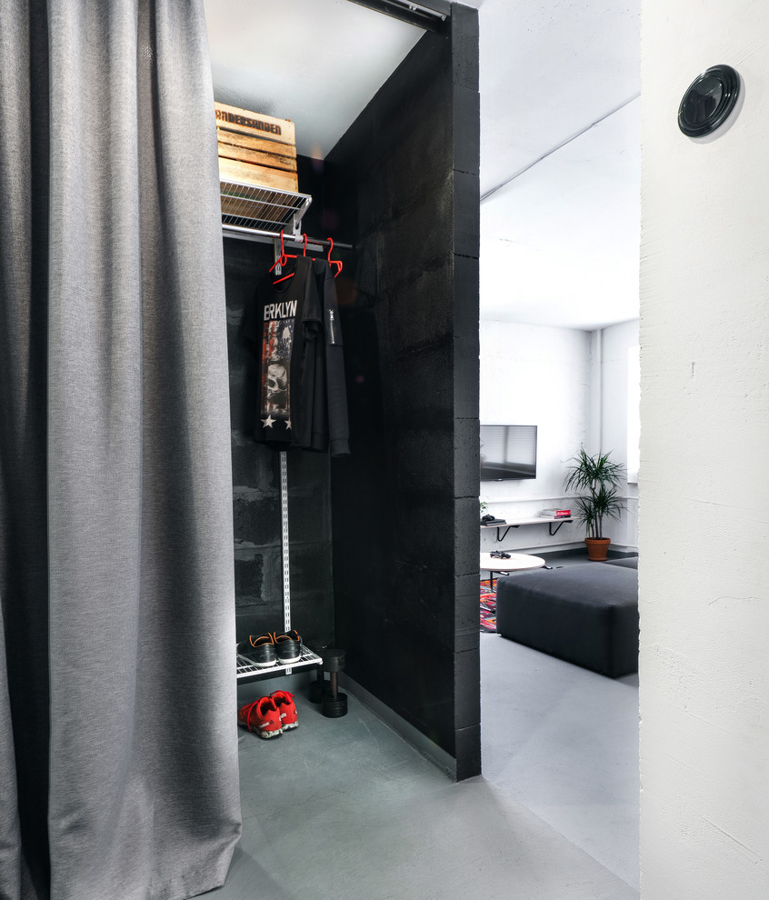 Photo of an industrial walk-in wardrobe for men in Other with grey floors.