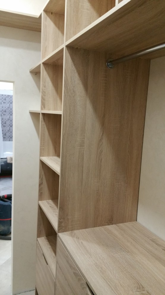 Example of a small porcelain tile and gray floor walk-in closet design in Moscow with flat-panel cabinets and light wood cabinets