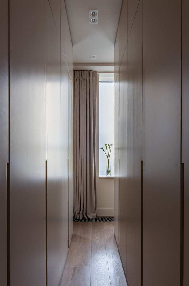 Imagen de armario unisex actual pequeño con armarios con paneles lisos, suelo de madera en tonos medios y puertas de armario de madera oscura